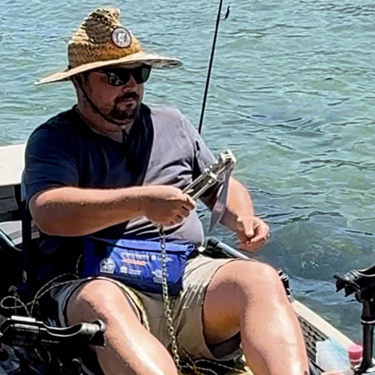 Kayak angler holding an Active Anchors DF200 releasable boat anchor with attached chain while seated on the water.
