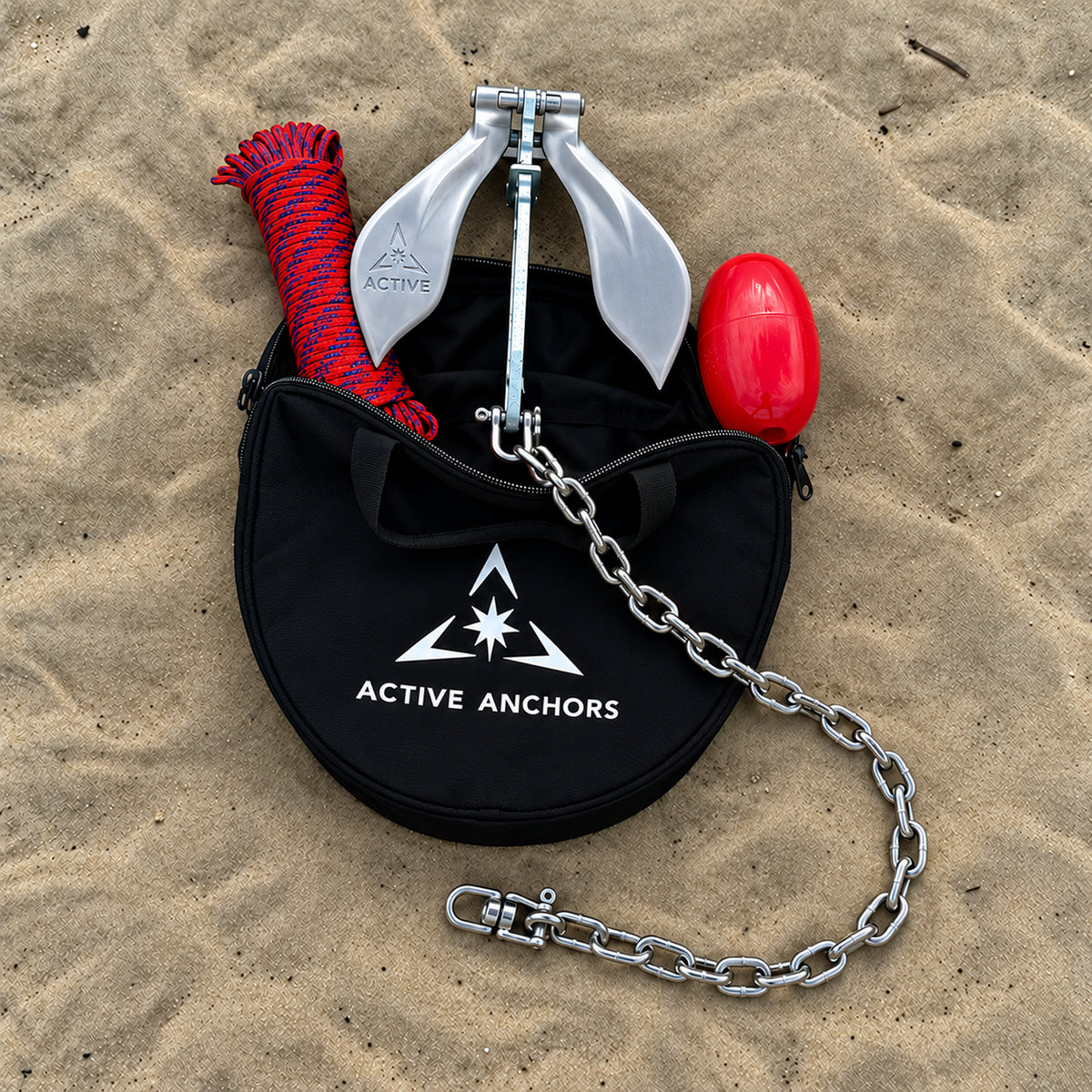 Active Anchors DF200 boat anchor with chain emerging from an open black storage bag, alongside coiled rope and a red float on sand.