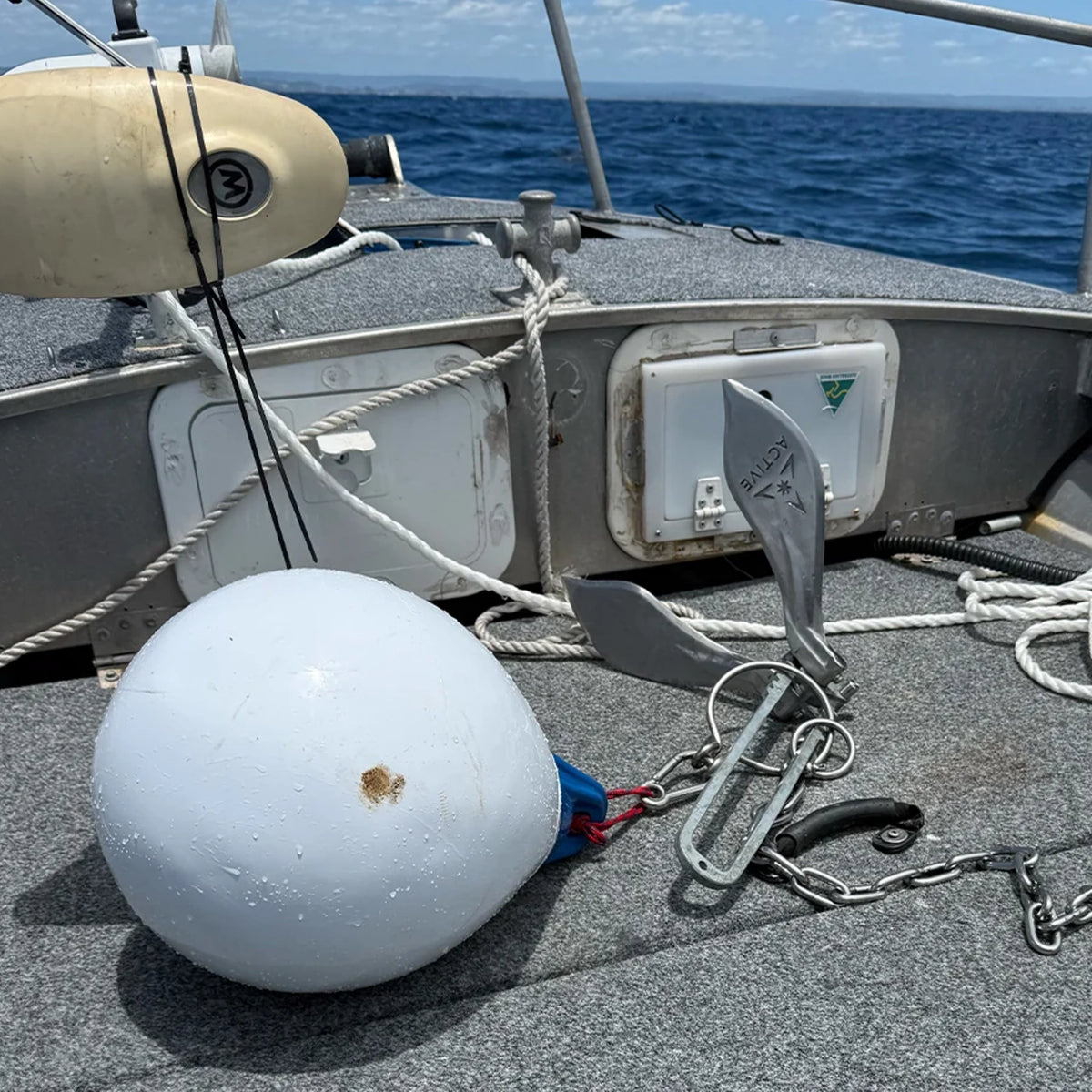 Active Anchors DF400 releasable marine anchor with chain and white buoy displayed on the deck of a fishing boat at sea.