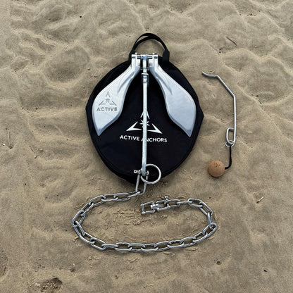 Active Anchors DF400 boat anchor with stainless steel flukes, chain, carry bag and release tool laid out on a sandy beach.