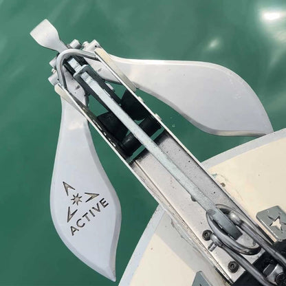 Active Anchors DF500 releasable marine anchor mounted on a boat's bow roller above the water, showing its curved stainless steel flukes.