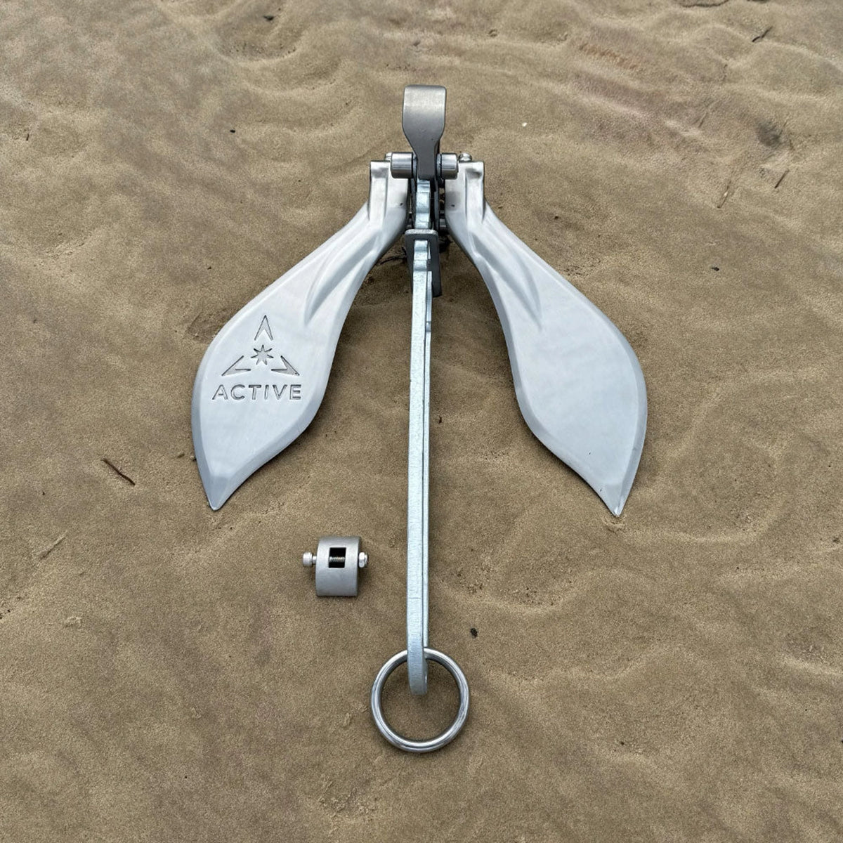 Active Anchors DF500 boat anchor displayed on a sandy beach with twin stainless steel flukes, galvanised shank and attachment ring.