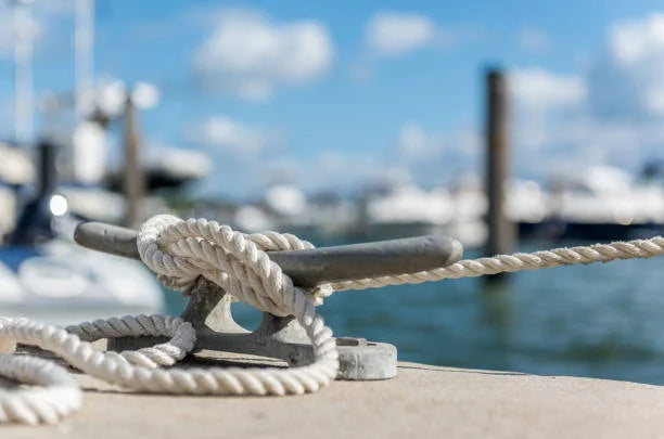 Image of a cleat on a dock-side with mooring rope tied to it.